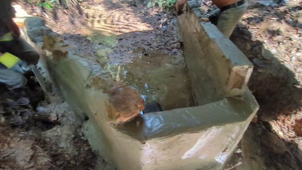Photo of a concrete block, rock, and cement weir being freshly cemented