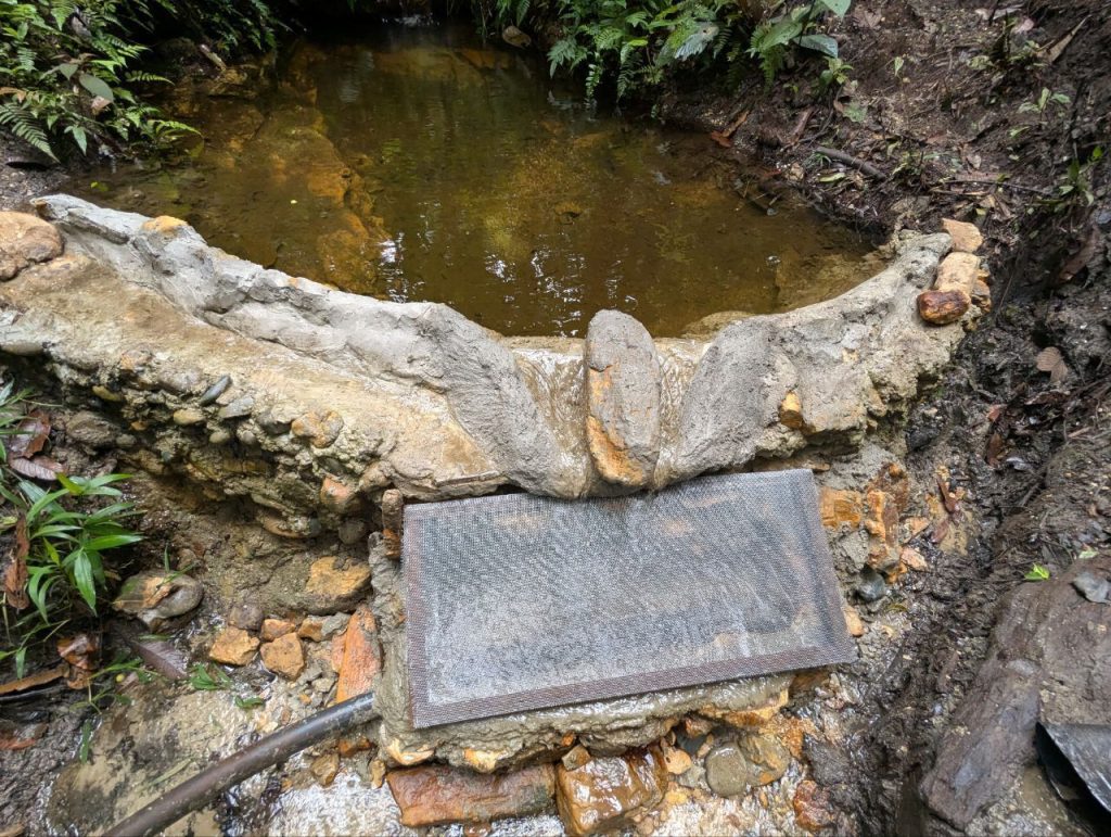 Photo of a rock-and-cement weir with an extended lip over the weir opening, created by cemented-over chicken wire